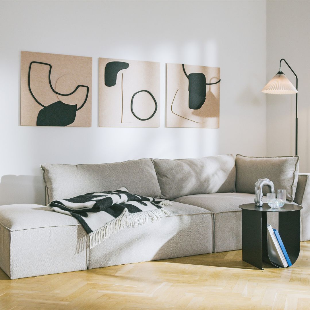 Artistic acoustic panels in minimalist black and beige design above a modern sofa.